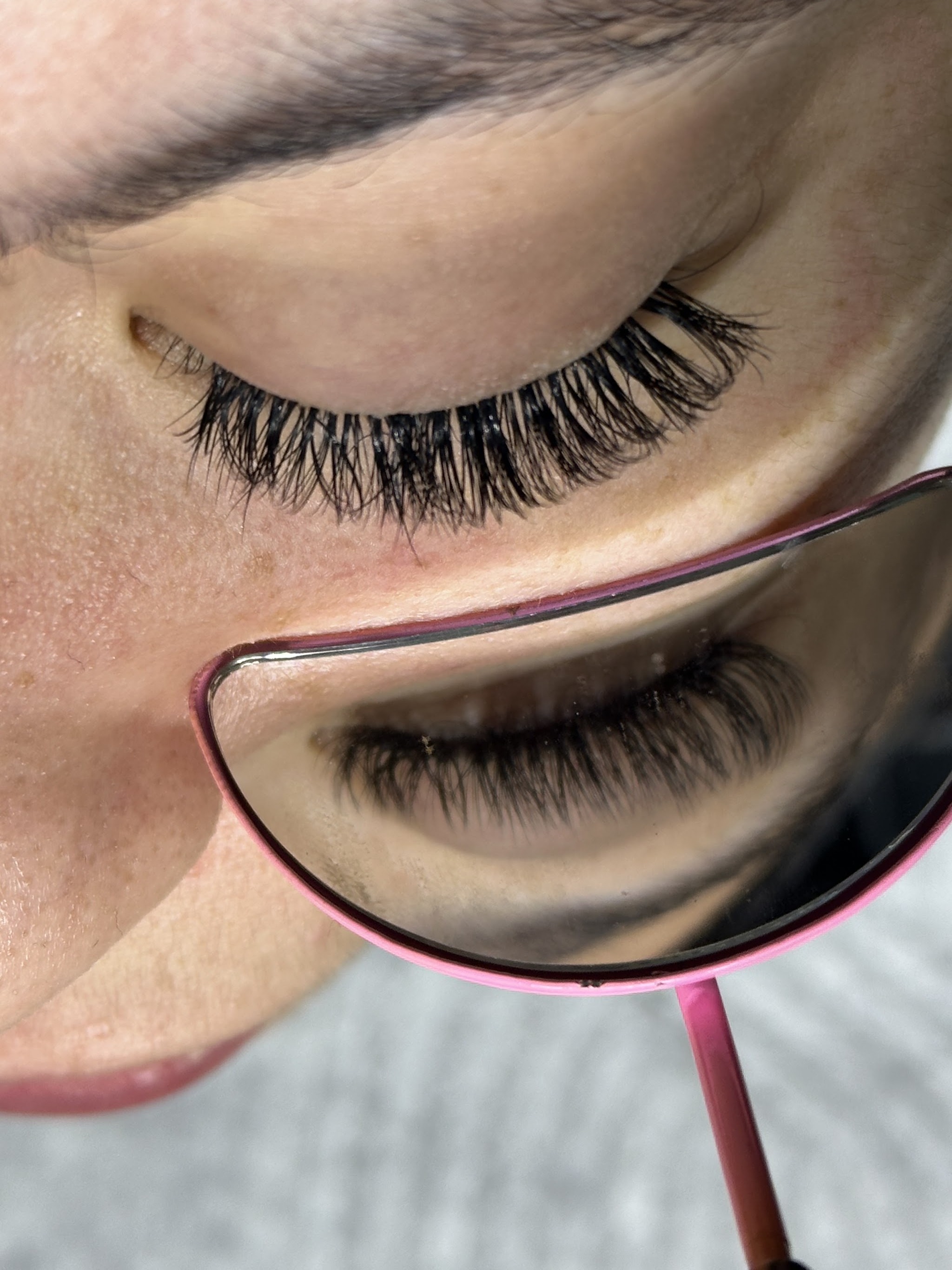 Gesloten oog met lash extensions en de lash spiegel eronder